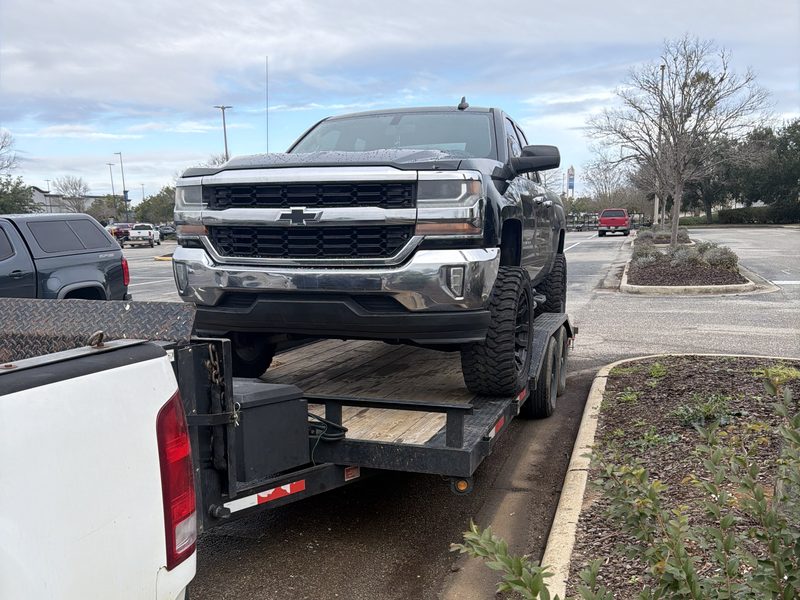 A lifted Chevy Silverado loaded on the car hauler trailer