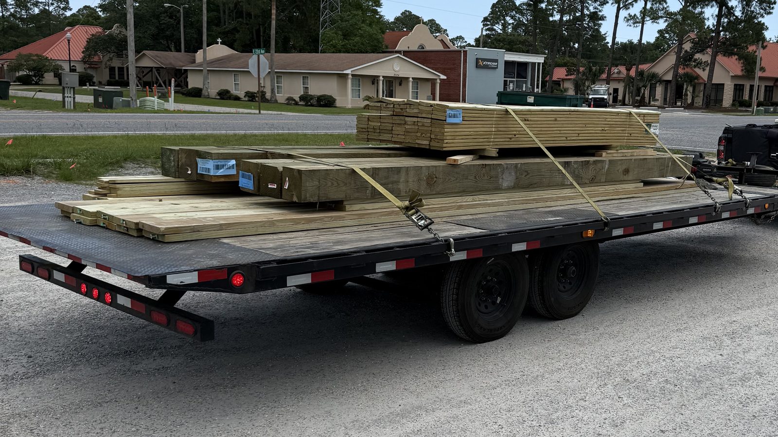 A One Way Trailer Rental deckover trailer loaded with strapped-down lumber, hitched up and ready to roll in Foley, Alabama